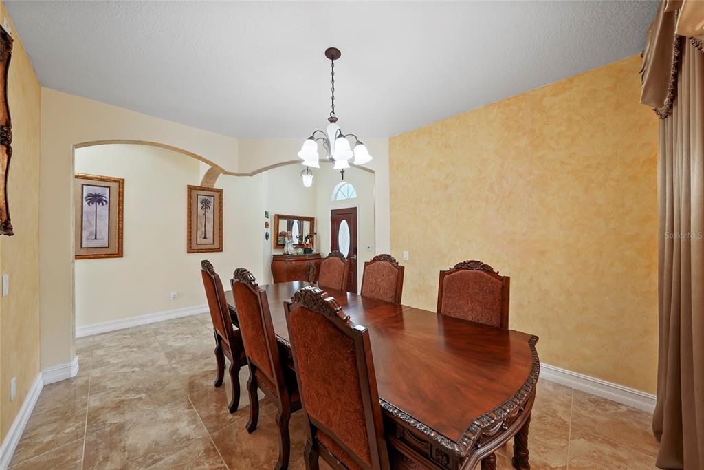 A formal dining room features a wooden table, upholstered chairs, and textured yellow walls — 3817 LANGDRUM DRIVE, WESLEY CHAPEL, FL