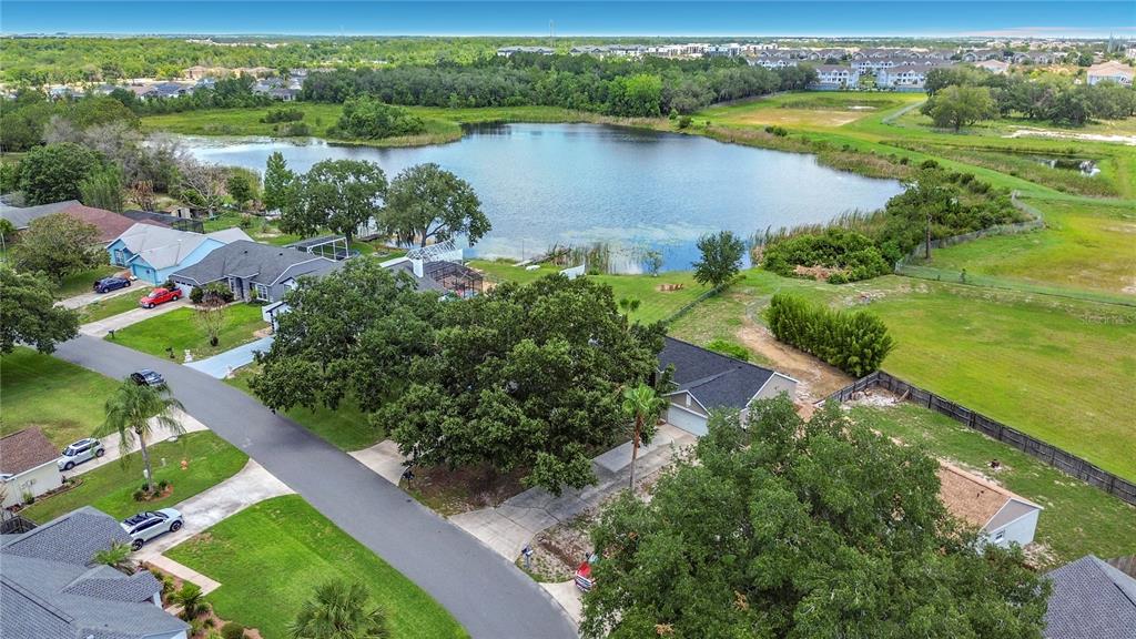An aerial view shows suburban houses with driveways and lawns bordering a large, calm lake — 210 ROBBINS REST CIRCLE, DAVENPORT, FL