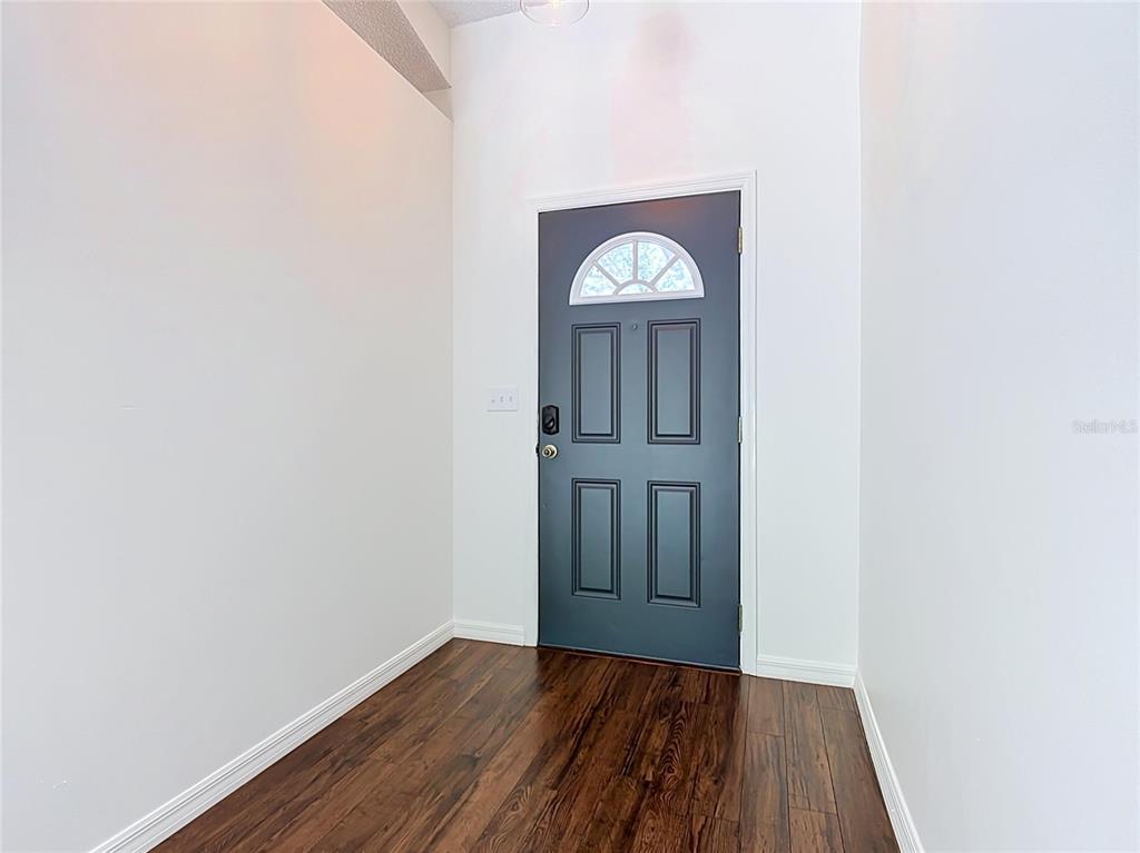 An entryway features dark wood flooring, white walls, and a dark gray front door — 210 ROBBINS REST CIRCLE, DAVENPORT, FL