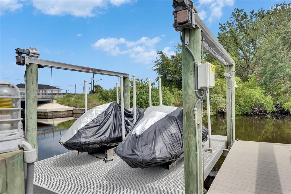 Two jet skis covered in protective tarps sit on a boat lift over water — 6512 SIMONE SHORES CIRCLE, APOLLO BEACH, FL