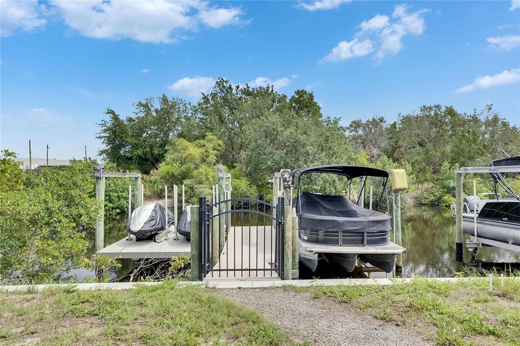 A boat dock with a gated walkway, a covered pontoon boat, and two jet skis — 6512 SIMONE SHORES CIRCLE, APOLLO BEACH, FL