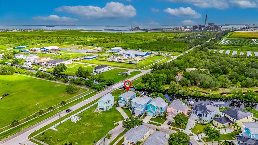 This aerial view shows a residential neighborhood with houses near a canal and industrial plant — 6512 SIMONE SHORES CIRCLE, APOLLO BEACH, FL