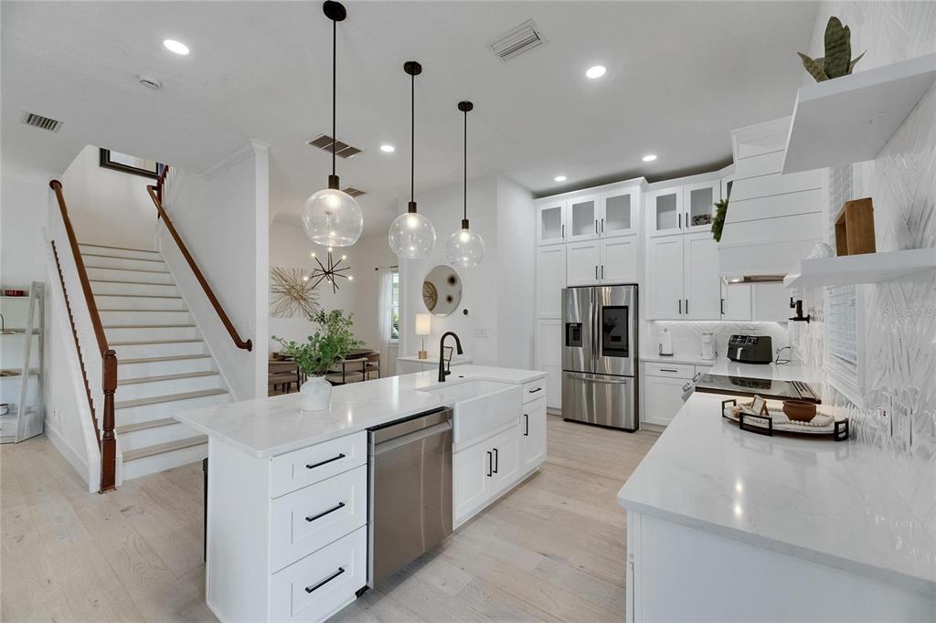 A modern white kitchen features a large island, stainless steel appliances, and an adjacent staircase — 6512 SIMONE SHORES CIRCLE, APOLLO BEACH, FL