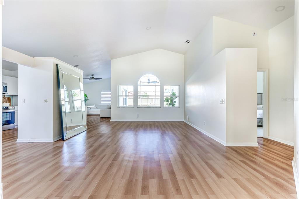 An open living area features light wood-look flooring, vaulted ceilings, and a large arched window — 10031 RIVER GLEN COURT, ORLANDO, FL