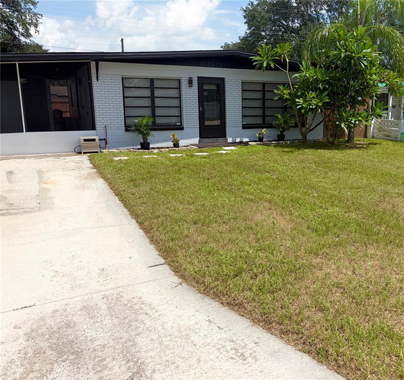 A single-story house with a white brick exterior, black trim, and a concrete driveway — 707 LAKEWOOD AVENUE, TAMPA, FL