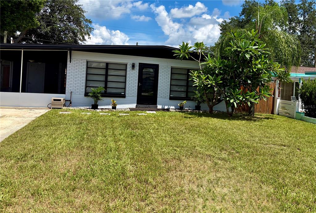 A single-story white brick house features a black front door and a covered side porch — 707 LAKEWOOD AVENUE, TAMPA, FL