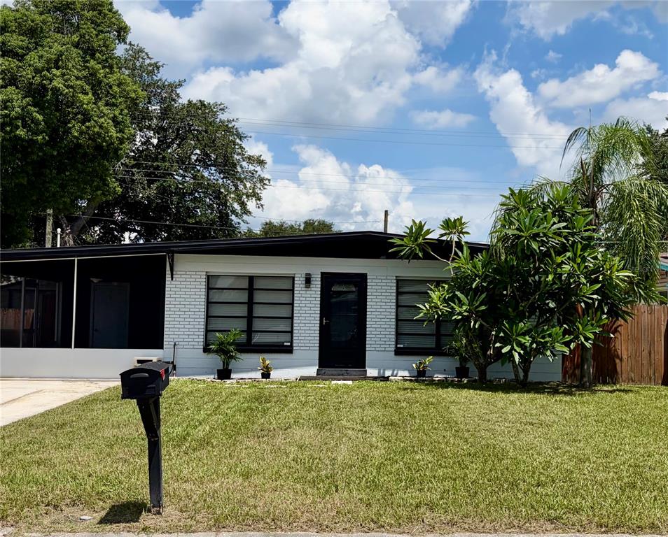A single-story house with white brick walls, a black roof, and a front lawn — 707 LAKEWOOD AVENUE, TAMPA, FL