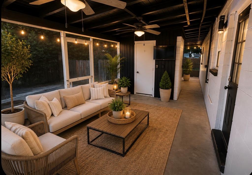 A covered outdoor patio features a sofa, armchairs, a coffee table, and string lights — 707 LAKEWOOD AVENUE, TAMPA, FL
