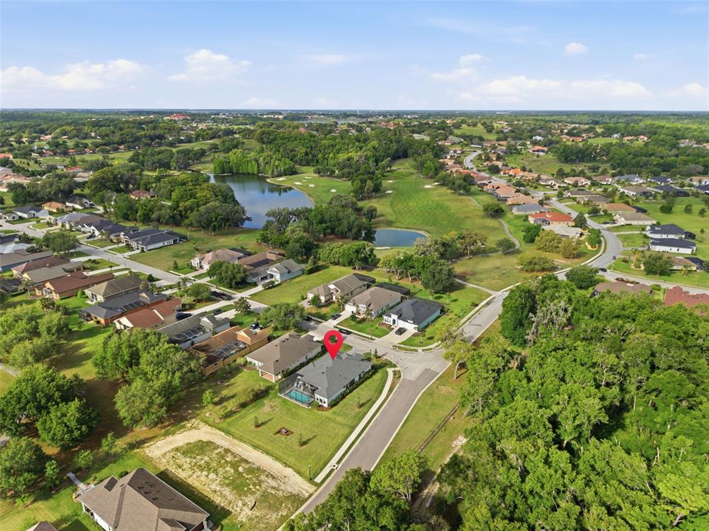 An aerial view shows a residential house with a pool in a suburban neighborhood — 13444 TRAILING MOSS DRIVE, DADE CITY, FL