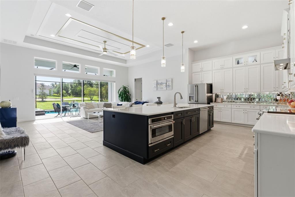 A modern open-concept kitchen and living area with a dark island and white cabinetry — 13444 TRAILING MOSS DRIVE, DADE CITY, FL
