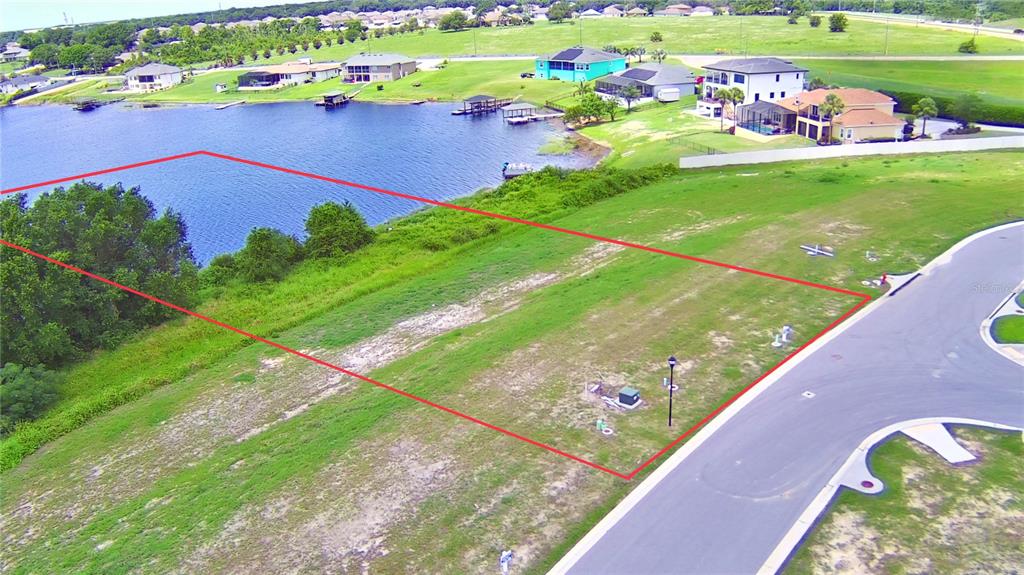 An aerial view shows a vacant, rectangular waterfront lot outlined in red next to a road — 4389 JULIANA LAKE DRIVE, AUBURNDALE, FL