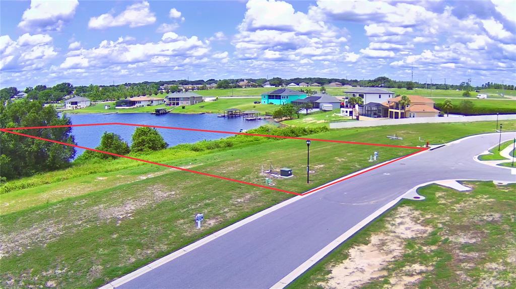 An aerial view shows a vacant waterfront lot outlined in red along a paved road — 4389 JULIANA LAKE DRIVE, AUBURNDALE, FL
