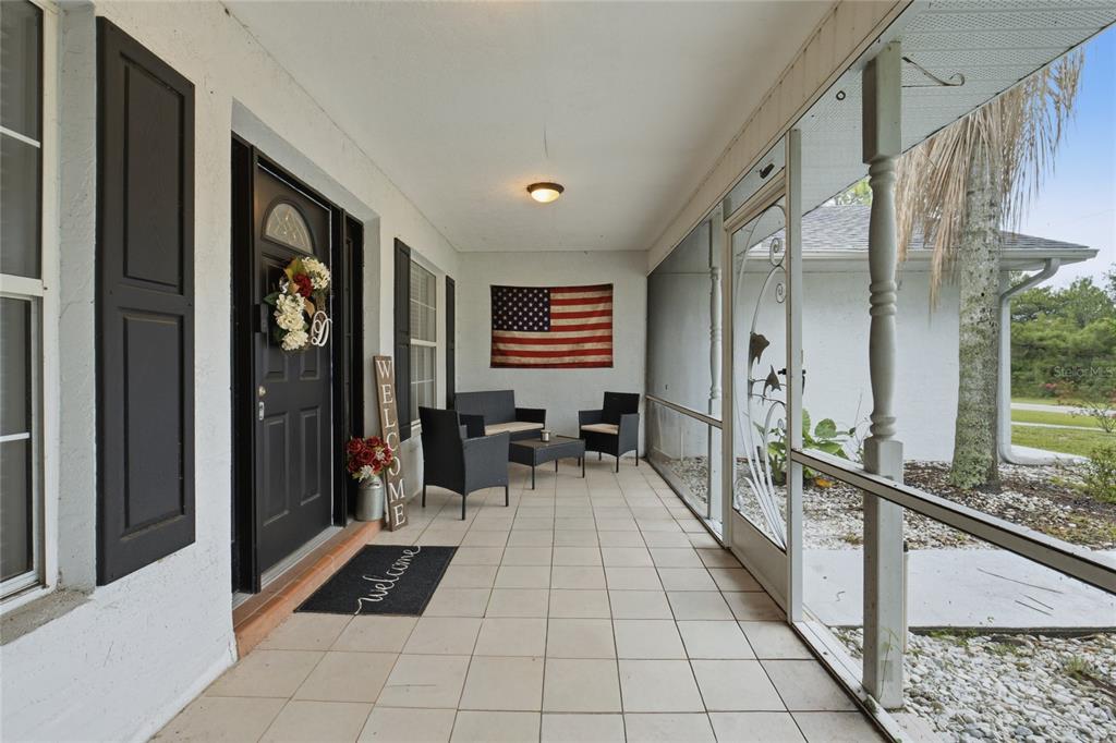 The exterior of a house features a screened front porch, a palm tree, and landscaping — 4353 W PINE RIDGE BOULEVARD, BEVERLY HILLS, FL