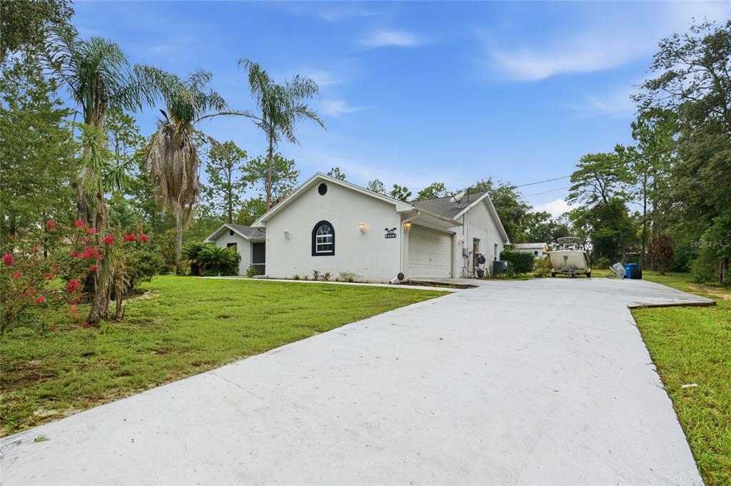 A white single-story house with a screened front porch sits on a grassy, landscaped lot — 4353 W PINE RIDGE BOULEVARD, BEVERLY HILLS, FL