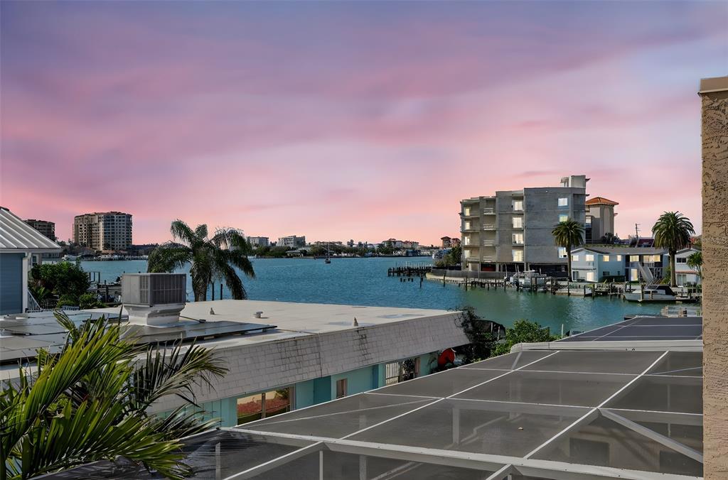 An elevated view of a waterfront canal at sunset with surrounding buildings and palm trees — 348 LARBOARD WAY, CLEARWATER BEACH, FL