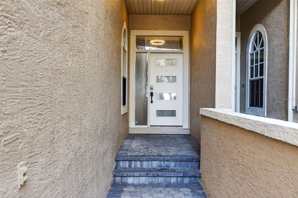 A white front door with four glass panels sits at the top of stone steps — 348 LARBOARD WAY, CLEARWATER BEACH, FL