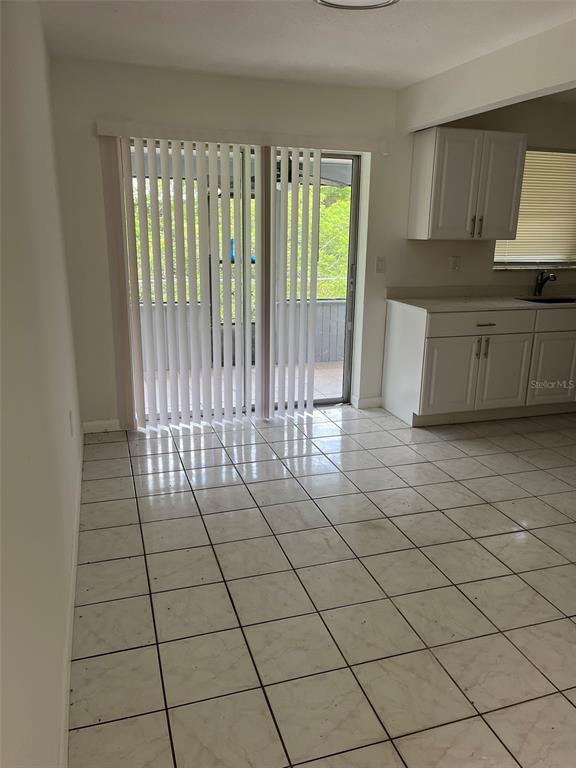 A dining area with white tile floors and sliding glass doors leading to a patio — 8956 SE 65TH WAY, OKEECHOBEE, FL