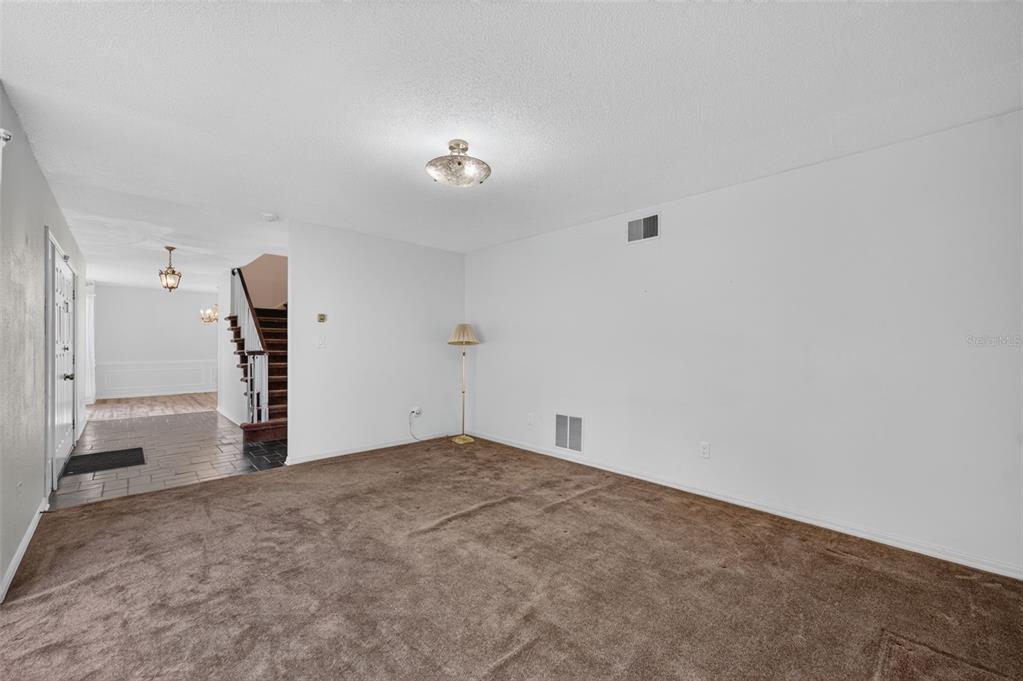 A carpeted living room features a ceiling light, a floor lamp, and a tiled entryway — 60 OAKLEIGH LANE, MAITLAND, FL