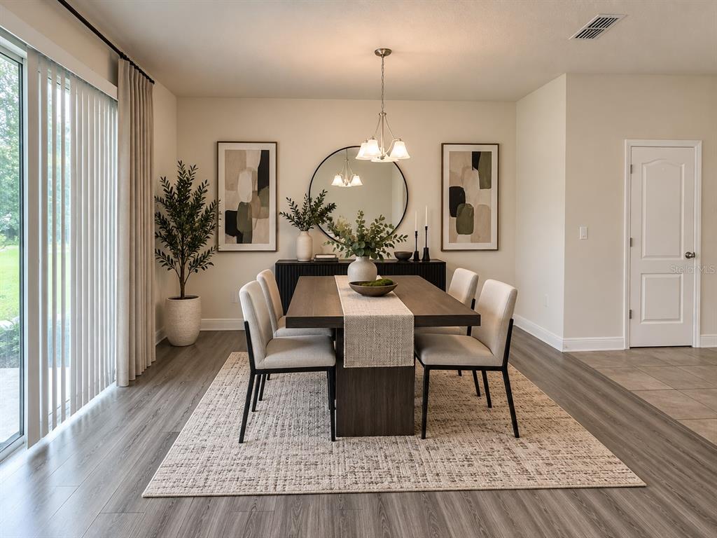 An open-concept living and dining room with light wood-look flooring and a sliding glass door — 2749 PLEASANT CYPRESS CIRCLE, KISSIMMEE, FL