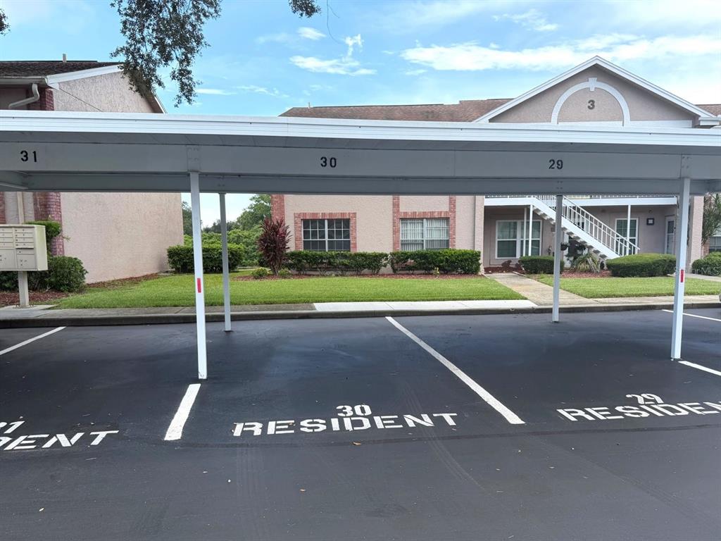 An outdoor covered parking area with numbered spaces in front of a residential apartment building — 4925 MYRTLE OAK DRIVE UNIT 25, NEW PORT RICHEY, FL