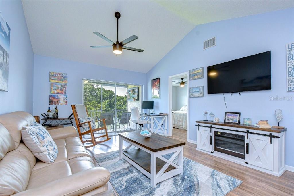 A living room features a beige sofa, a coffee table, a television, and a sliding door — 4925 MYRTLE OAK DRIVE UNIT 25, NEW PORT RICHEY, FL