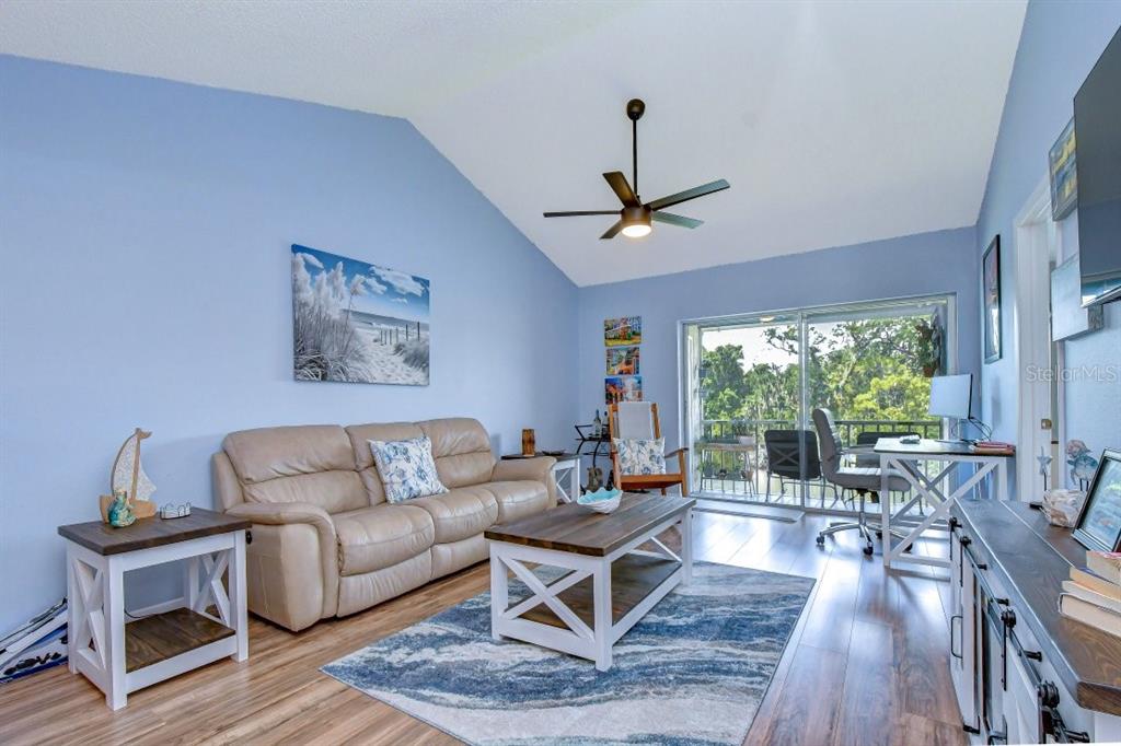 A living room with light blue walls, a beige sofa, and a sliding glass door — 4925 MYRTLE OAK DRIVE UNIT 25, NEW PORT RICHEY, FL