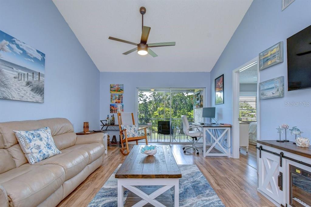 A living room with light blue walls, a beige sofa, wood floors, and a ceiling fan — 4925 MYRTLE OAK DRIVE UNIT 25, NEW PORT RICHEY, FL