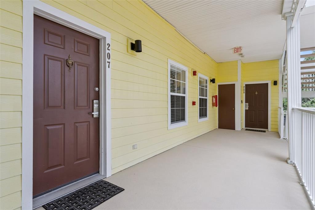 A yellow exterior hallway features two brown doors numbered 207 and 205 — 207 LUCAYA LOOP UNIT 207, DAVENPORT, FL