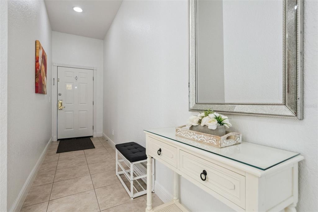 An entryway features a white door, a console table with a mirror, and tiled flooring — 207 LUCAYA LOOP UNIT 207, DAVENPORT, FL