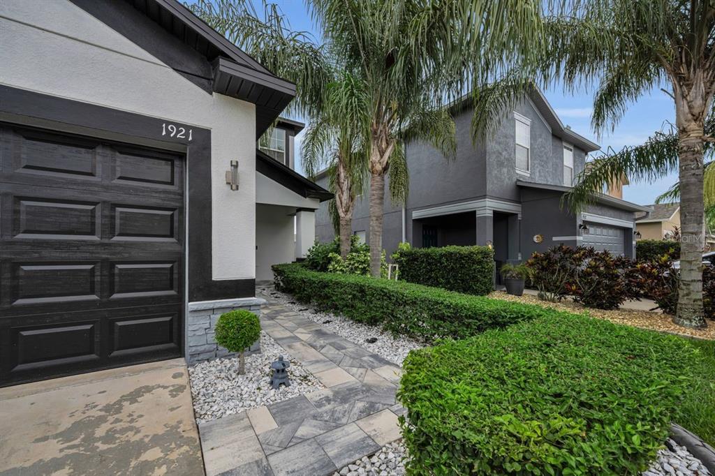 A paved walkway leads to the front entrance of a house with a palm tree — 1921 HAWKS VIEW DRIVE, RUSKIN, FL