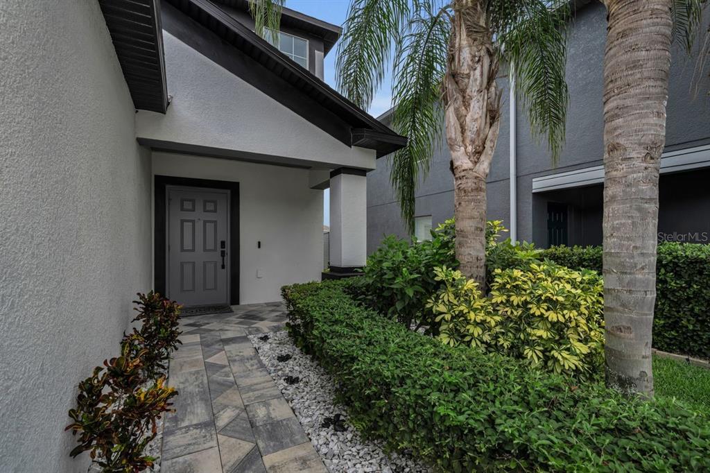 An entryway features a white door, a carpeted staircase, wood-look flooring, and wall art — 1921 HAWKS VIEW DRIVE, RUSKIN, FL