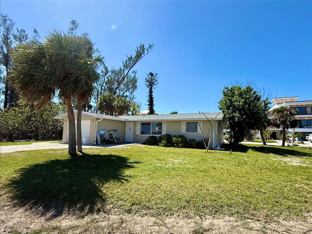 A single-story house with a light-colored exterior, a grassy front yard, and palm trees — 1170 LITTLE COURT, ENGLEWOOD, FL