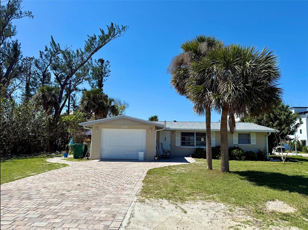 A single-story house with a paved driveway, a garage, and palm trees in the front yard — 1170 LITTLE COURT, ENGLEWOOD, FL