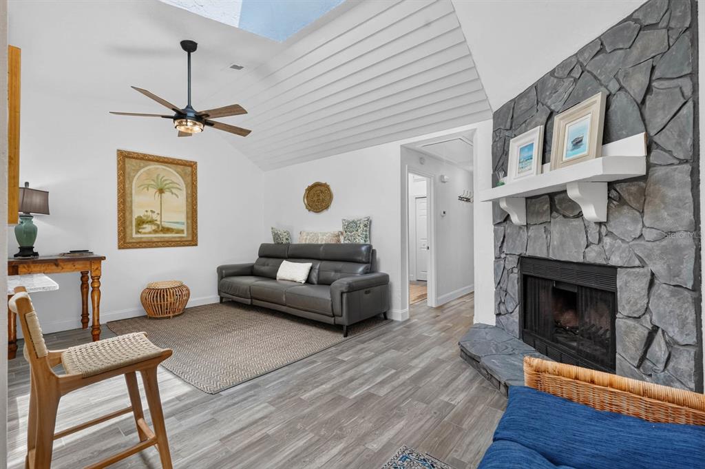 A living room features a stone fireplace, vaulted ceiling, gray flooring, and a gray sofa — 5 ARBOR LAKE PARK, ORMOND BEACH, FL
