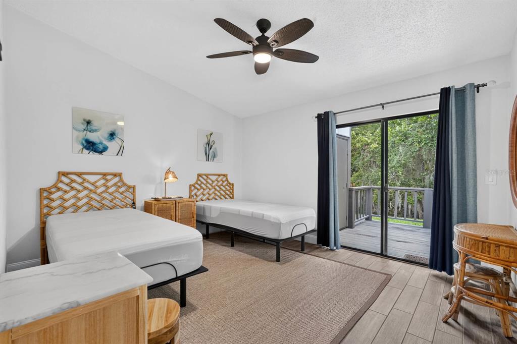 A bedroom with two beds, a ceiling fan, and a sliding door leading to a deck — 5 ARBOR LAKE PARK, ORMOND BEACH, FL