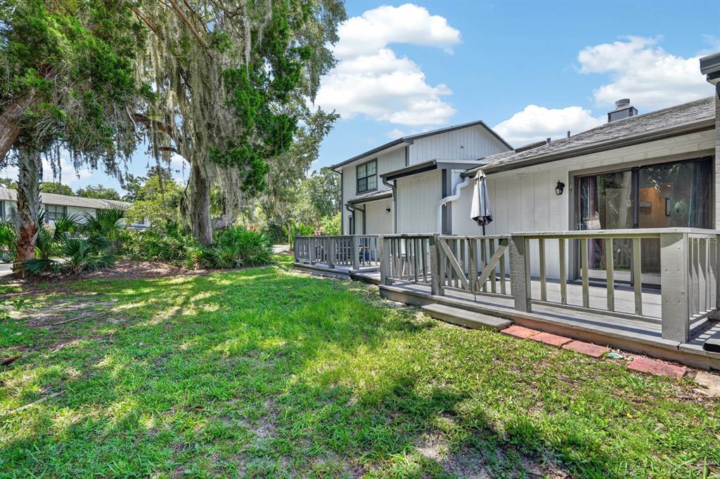 A wooden deck extends from the back of a two-story house near a grassy yard — 5 ARBOR LAKE PARK, ORMOND BEACH, FL