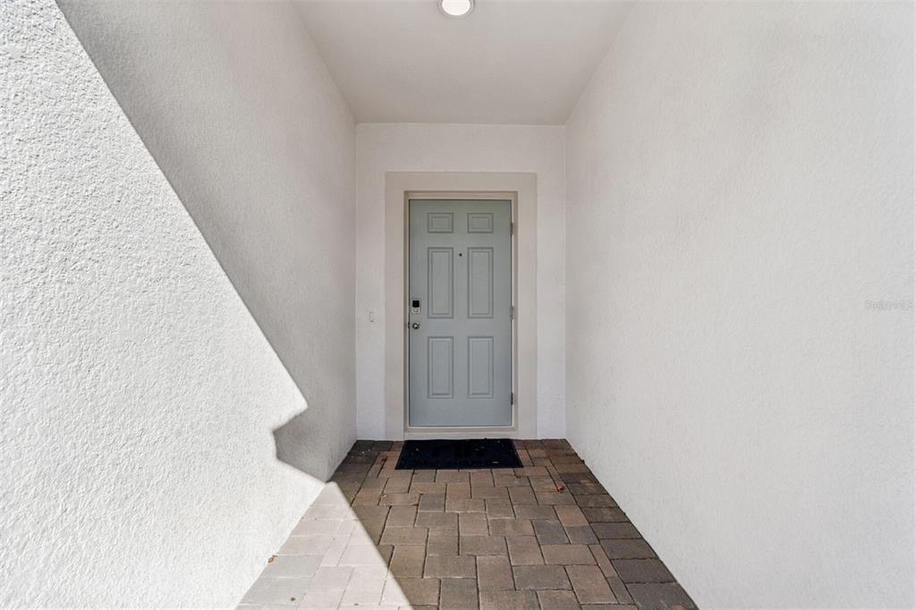 A light blue front door is centered at the end of a paved entryway — 12915 CASTLE OAKS DRIVE, HUDSON, FL