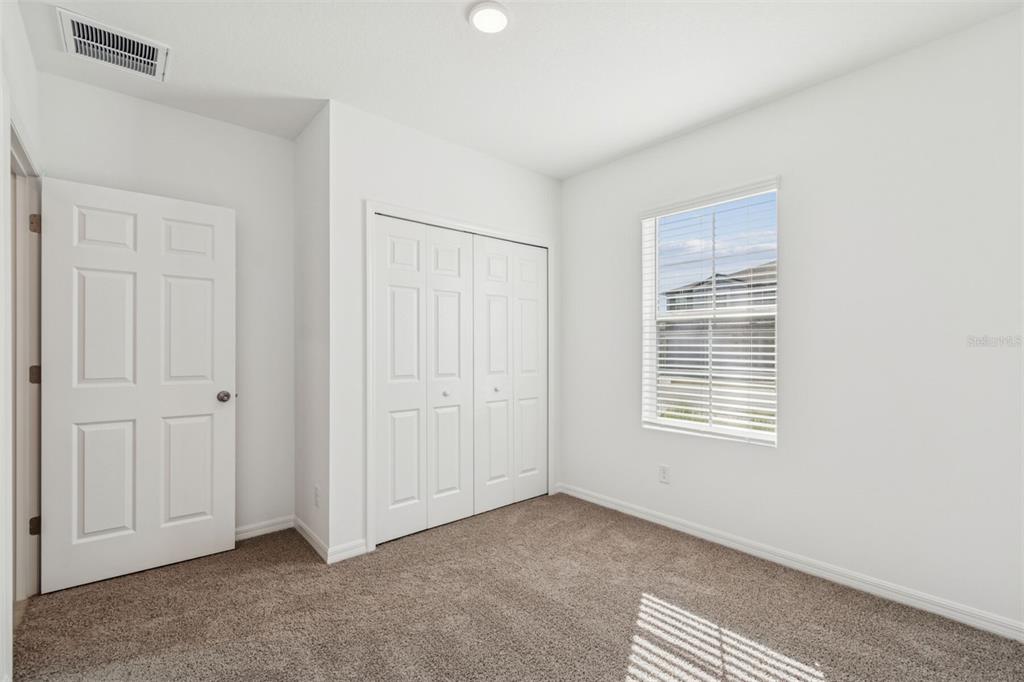 A bedroom with white walls, brown carpet, a closet, and a window with blinds — 12915 CASTLE OAKS DRIVE, HUDSON, FL