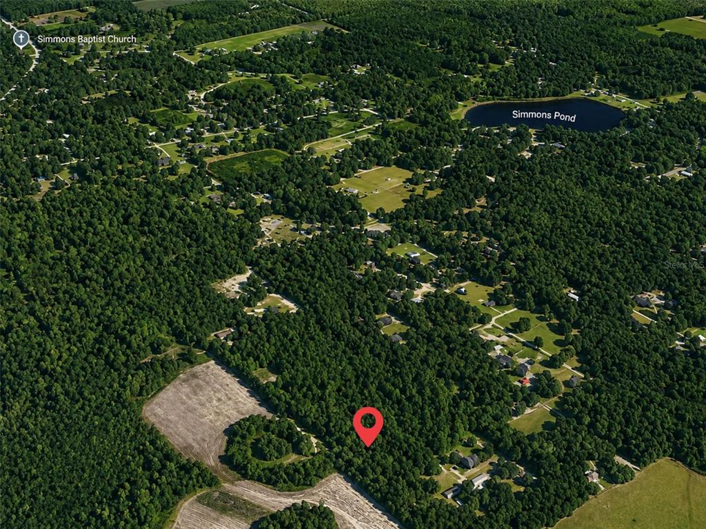 This aerial view shows a wooded lot marked with a pin near Simmons Pond — XX, CITRA, FL