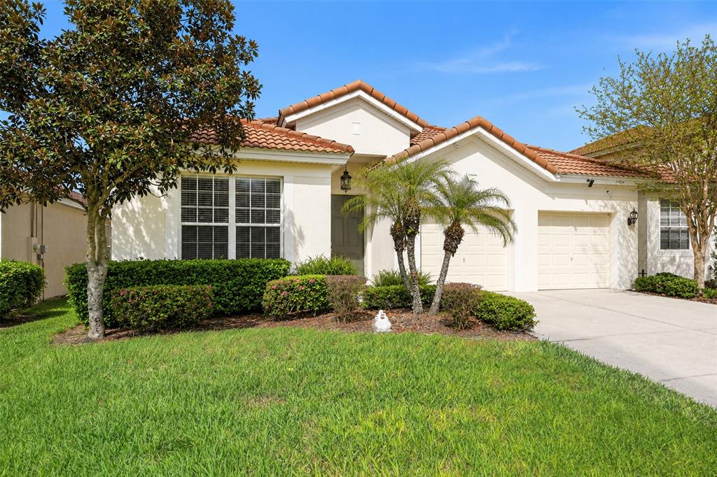 A single-story house with a tile roof, two garage doors, and a front lawn — 7755 GRASSENDALE STREET, KISSIMMEE, FL