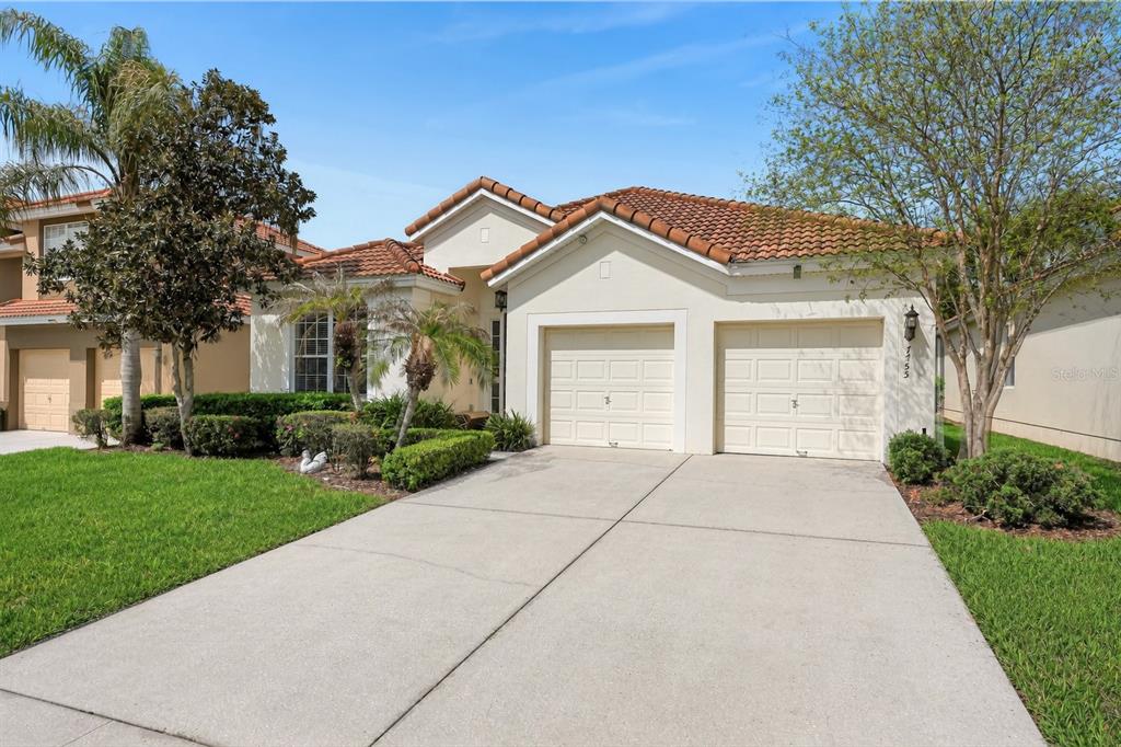 A single-story house with a two-car garage, tile roof, and a concrete driveway — 7755 GRASSENDALE STREET, KISSIMMEE, FL