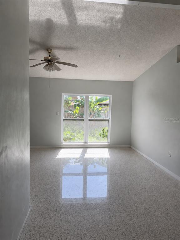 A living room with light gray walls, a vaulted ceiling, and speckled terrazzo flooring — 2843 BAY STREET, SARASOTA, FL