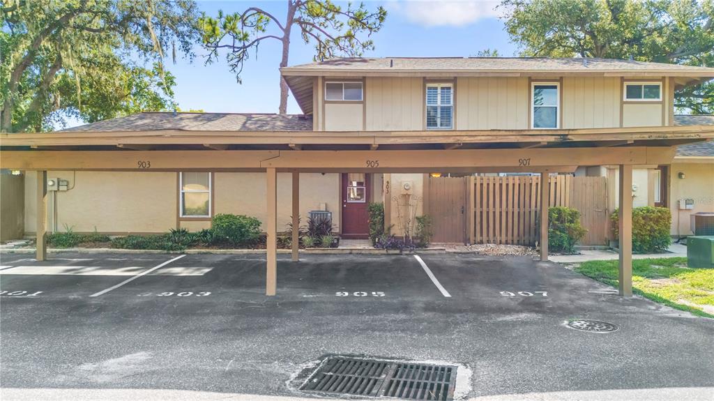 A two-story building features a covered carport with three numbered parking spaces in front — 903 BUCK COURT, BRANDON, FL