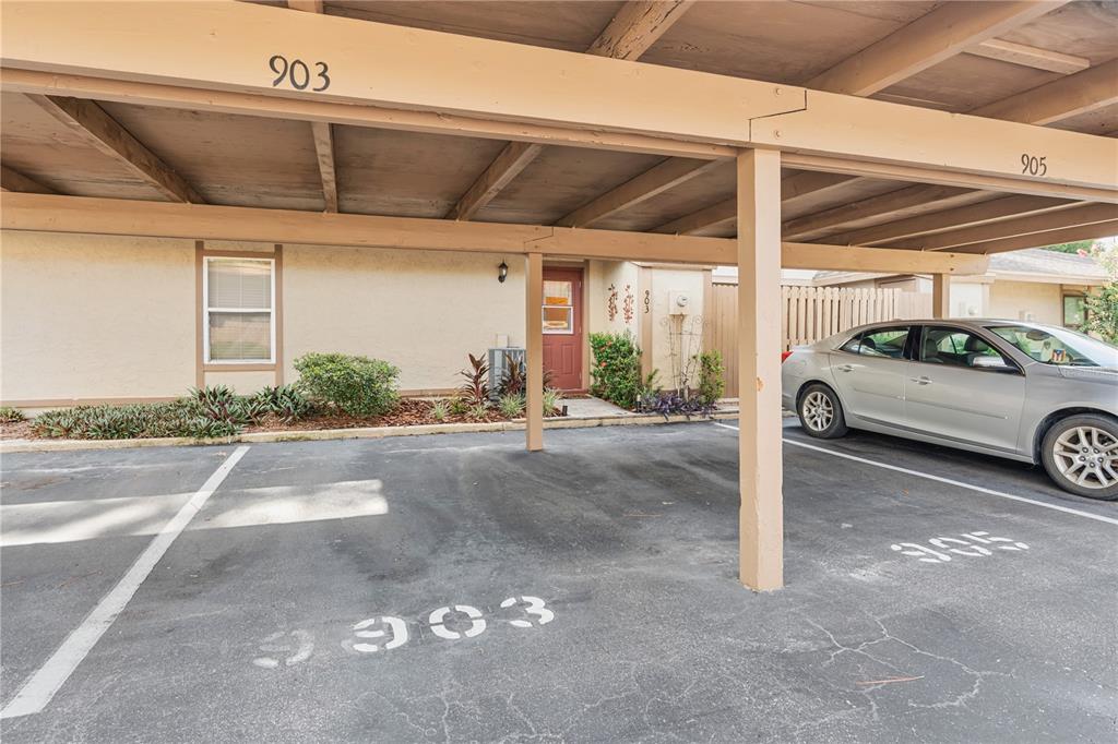 A covered parking area features two numbered spaces in front of a residential building entrance — 903 BUCK COURT, BRANDON, FL