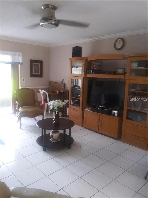 A living room features a ceiling fan, tiled floors, a wooden entertainment center, and an armchair — 706 OAKGROVE DRIVE UNIT 114, BRANDON, FL