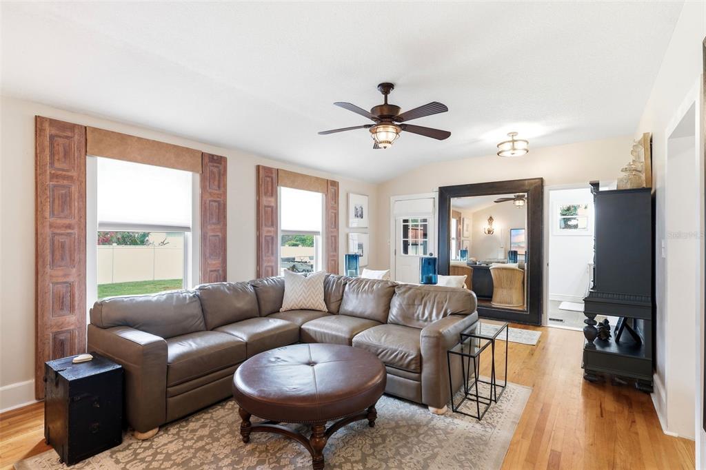 A living room features a leather sectional, round ottoman, ceiling fan, and large wall mirror — 47 DAVIS AVENUE, UMATILLA, FL