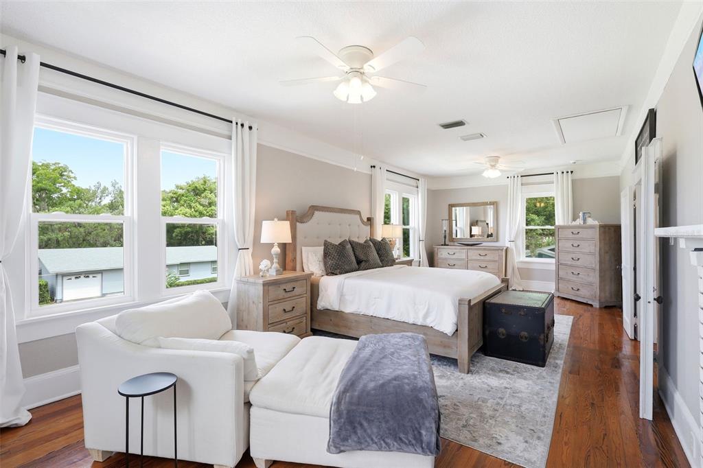 A bedroom features a bed, white armchair, wooden furniture, and hardwood floors — 47 DAVIS AVENUE, UMATILLA, FL