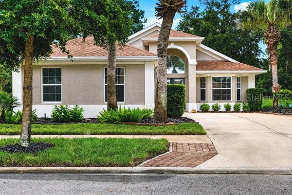 A single-story house with a beige stucco exterior, a brown shingled roof, and a driveway — 54 SHINNECOCK DRIVE, PALM COAST, FL