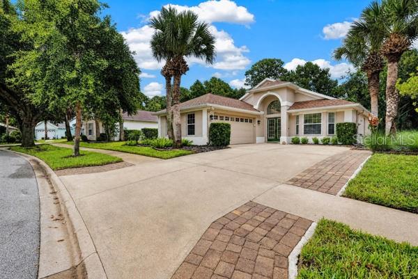 A single-story suburban house with a concrete driveway, palm trees, and a two-car garage — 54 SHINNECOCK DRIVE, PALM COAST, FL
