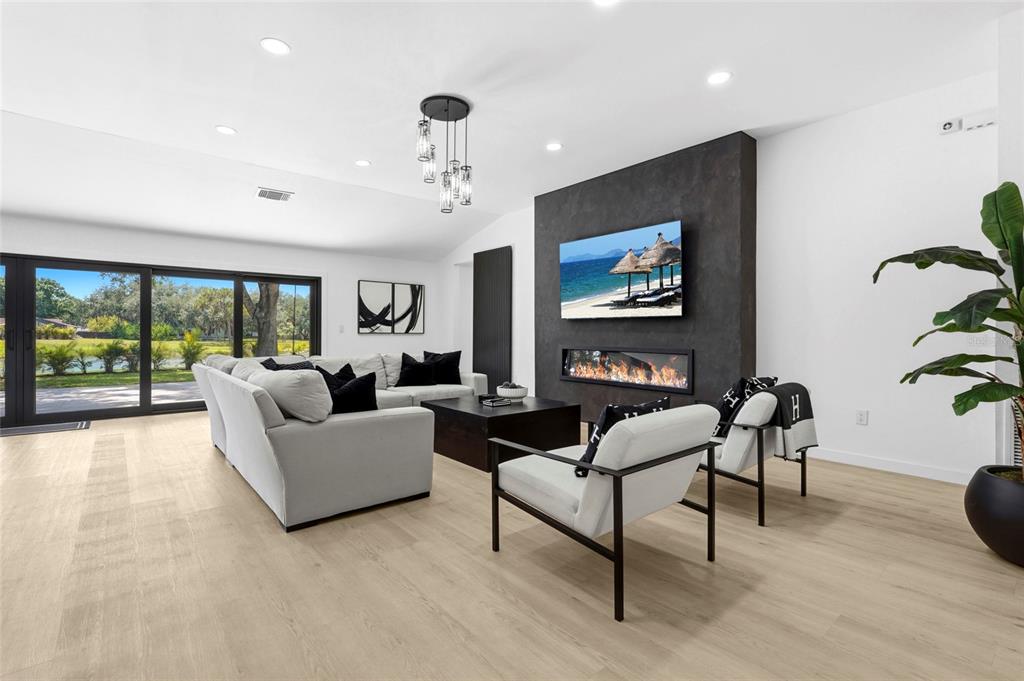 A modern open-concept living room features a white sectional sofa, black accents, and large windows — 906 136TH STREET E, BRADENTON, FL